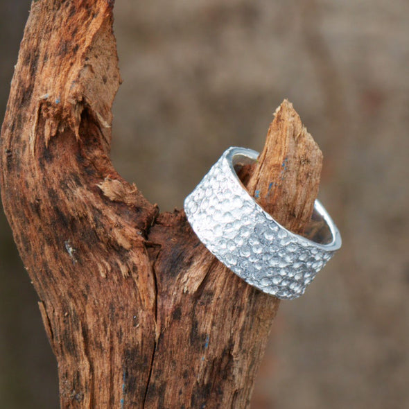 ein-breiter-ring-mit-einer-oberflaeche-voller-krater-der-ring-ist-ca-zehn-millimeter-breit-und-besteht-aus-recyceltem-sterling-silber-geeignet-als-trauring-oder-schmuckring-fuer-menschen-die-auffaellige-ringe-moegen-die-ringe-werden-von-hand-in-unserer-goldschmiede-in-frankfurt-am-main-angefertigt-und-sind-individuell-anpassbar-alexandra-baum-schmuck