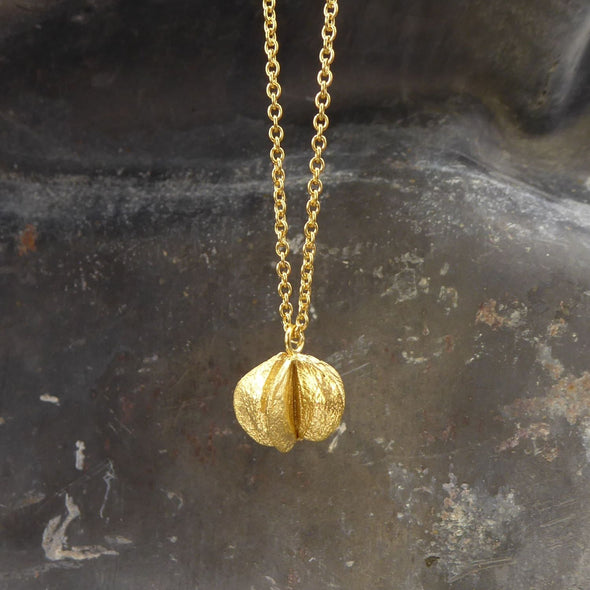 eine-kette-mit-einem-anhaenger-in-form-einer-samenkapsel-der-prunkspiere-the-bride-die-kette-besteht-aus-vergoldetem-recycling-sterling-silber-als-verschluss-der-kette-ist-ein-karabiner-befestigt-den-man-auf-zwei-verschiedene-laengen-einhaken-kann-nachhaltiger-schmuck-von-hand-gefertigt-in-unserer-goldschmiede-in-frankfurt-bockenheim