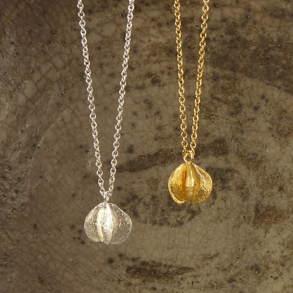 zwei-ketten-mit-anhaengern-in-form-von-samenkapseln-eine-kette-besteht-aus-vergoldetem-recycling-sterling-silber-und-die-andere-aus-recycling-silber-als-verschluss-der-ketten-ist-jeweils-ein-karabiner-befestigt-den-man-auf-zwei-verschiedene-laengen-einhaken-kann-nachhaltiger-schmuck-von-hand-gefertigt-in-unserer-goldschmiede-in-frankfurt-bockenheim