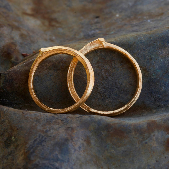 zwei-schlichte-handgefertigte-astringe-mit-feiner-besonderer-struktur-von-echten-aestchen-abgeformt-auf-der-oberseite-befindet-sich-ein-blattansatz-in-gelbgold-aus-unserer-goldschmiede-in-frankfurt-auch-in-fairtrade-gold-oder-fairmined-silber-erhaeltlich-breite-des-rings-ca-drei-millimeter-die-ringe-sind-auch-als-trauringe-geeignet