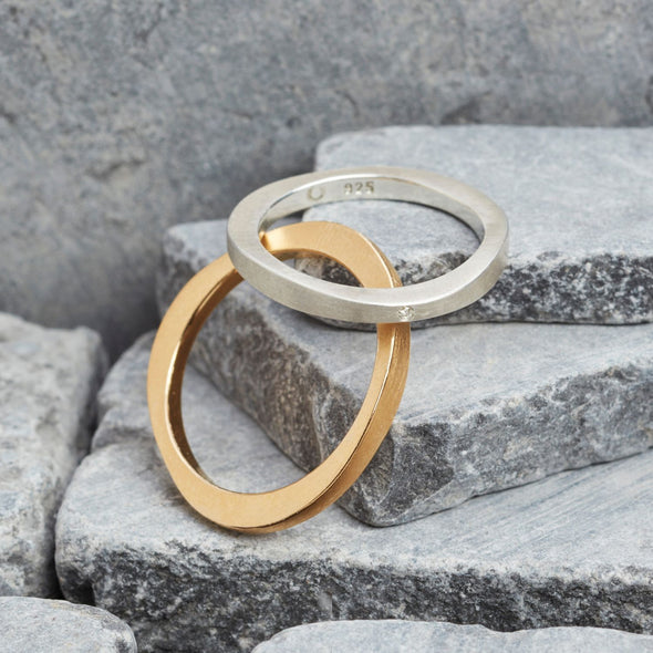 eheringe-mit-dem-namen-durch-dick-und-duenn-der-herrenring-besteht-aus-rosegold-und-der-damenring-aus-sterling-silber-er-ist-mit-3-einzelnen-brillanten-besetzt-die-form-ist-klassisch-aber-leicht-unregelmaessig-an-manchen-stellen-dicker-an-manchen-stellen-duenner-ein-design-trauring-der-sich-von-der-masse-abhebt-die-ringe-werden-von-hand-in-unserer-goldschmiede-in-frankfurt-am-main-angefertigt