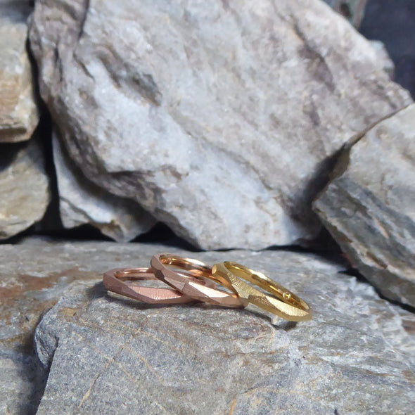 drei-ganz-schmale-ringe-mit-vielen-unregelmaessigen-facetten-beziehungsweise-polygonen-flaechen-die-ringe-sind-ca-zweieinhalb-millimeter-breit-und-bestehen-aus-gelbgold-rosegold-oder-rotgold-sie-sind-auch-in-fairtrade-gold-erhaeltlich-design-trauringe-oder-verlobungsringe-die-nicht-von-der-stange-sind-die-ringe-werden-von-hand-in-unserer-goldschmiede-in-frankfurt-am-main-angefertigt-alexandra-baum-schmuck