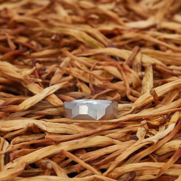 ein-breiterer-ring-mit-vielen-unregelmaessigen-facetten-beziehungsweise-polygonen-flaechen-der-ring-ist-ca-sechseinhalb-millimeter-breit-und-besteht-aus-palladiumweissgold-die-ringe-werden-von-hand-in-unserer-goldschmiede-in-frankfurt-am-main-angefertigt-und-sind-individuell-anpassbar-alexandra-baum-schmuck