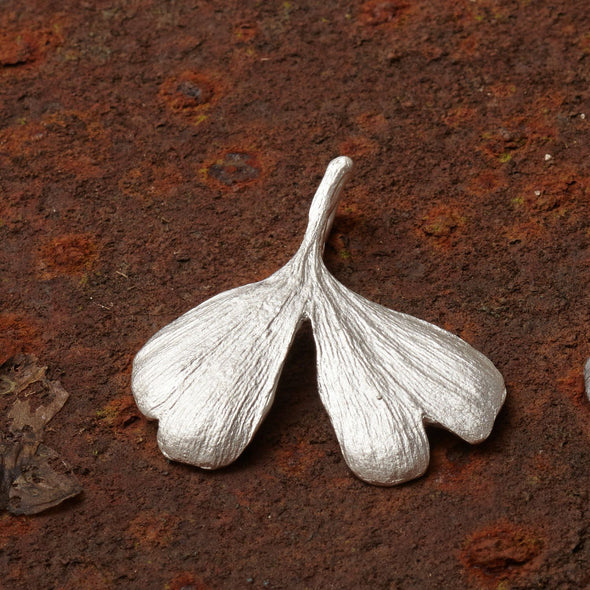 mittelgroßer-handgefertigter-ginkgo-anhänger-mit-feiner-struktur-von-echten-ginkgoblaettern-abgeformt-ohne-kette-in-sterling-silber-aus-unserer-goldschmiede-in-frankfurt-auch-in-fairtrade-gold-erhaeltlich-geschwungene-form-mit-einem-schlitz-und-wellen-an-den-blattspitzen-ungefaehr-37-millimeter