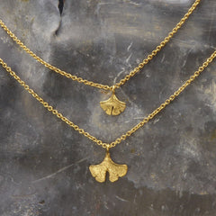 zwei-handgefertigte-ginkgo-anhaenger-in-verschiedenen-groessen-an-zarter-ankerkette-in-silber-vergoldet-oder-echtgold-aus-unserer-goldschmiede-in-frankfurt-auch-in-fairtrade-gold-erhaeltlich
