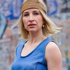 ein-blondes-model-traegt-gras-ohrhaenger-in-der-groesseren-variante-mit-einem-eirigen-anhaenger-mit-einer-struktur-von-echtem-gras-zum-befestigen-im-ohr-haben-die-ohrringe-einen-buegel-der-mit-einem-silikonroehrchen-verschlossen-wird-die-ohrringe-bestehen-aus-vergoldetem-recycling-sterling-silber-nachhaltiger-schmuck-von-hand-gefertigt-in-unserer-goldschmiede-in-frankfurt-bockenheim-alexandra-baum-schmuck