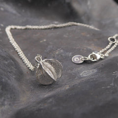 eine-kette-mit-einem-anhaenger-in-form-einer-samenkapsel-der-prunkspiere-the-bride-die-kette-besteht-aus-recycling-sterling-silber-als-verschluss-der-kette-ist-ein-karabiner-befestigt-den-man-auf-zwei-verschiedene-laengen-einhaken-kann-nachhaltiger-schmuck-von-hand-gefertigt-in-unserer-goldschmiede-in-frankfurt-bockenheim