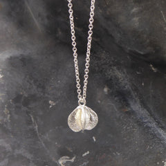 eine-kette-mit-einem-anhaenger-in-form-einer-samenkapsel-der-prunkspiere-the-bride-die-kette-besteht-aus-recycling-sterling-silber-als-verschluss-der-kette-ist-ein-karabiner-befestigt-den-man-auf-zwei-verschiedene-laengen-einhaken-kann-nachhaltig-und-von-hand-gefertigt-in-unserer-goldschmiede-in-frankfurt-bockenheim